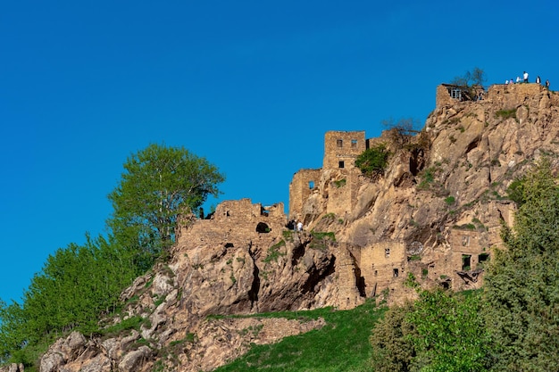 Touristes parmi les ruines de l'ancien village abandonné de Gamsutl sur une falaise au Daghestan