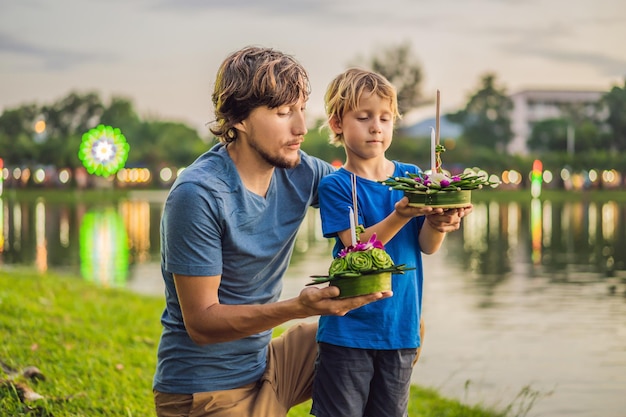 Les touristes père et fils tiennent le loy krathong dans ses mains et sont sur le point de le lancer dans l'eau