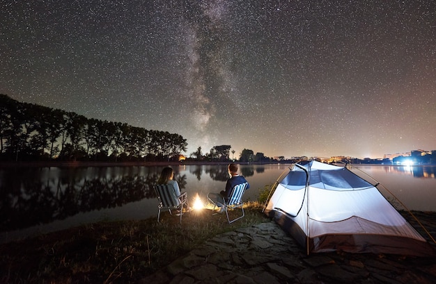 Touristes près de la tente au bord du lac la nuit