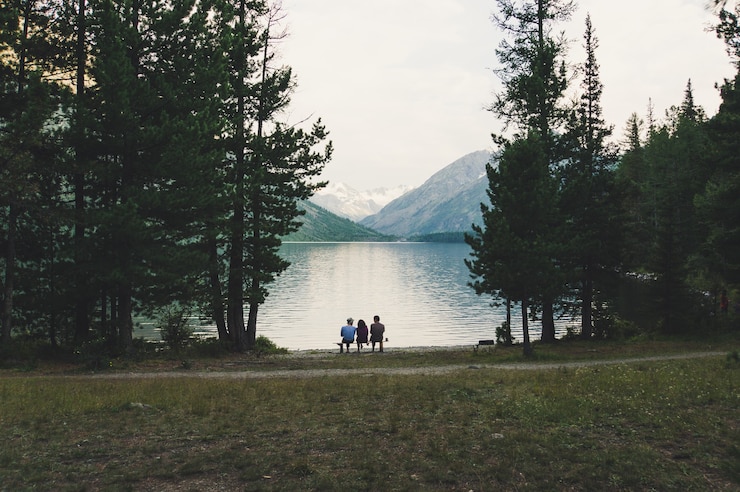 Photo les touristes s'assoient sur un banc au bord du lac alpin et admirent la belle vue dans la lumière du soir.