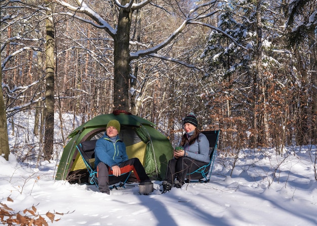 Touristes à la tente dans la forêt enneigée