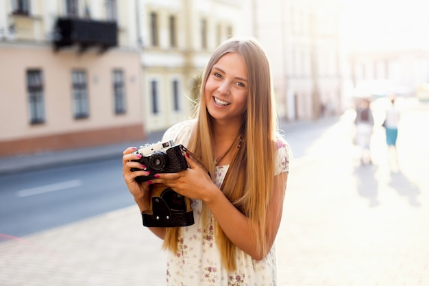 Photo touristique de belle jeune femme poring sur la rue en été avec caméra