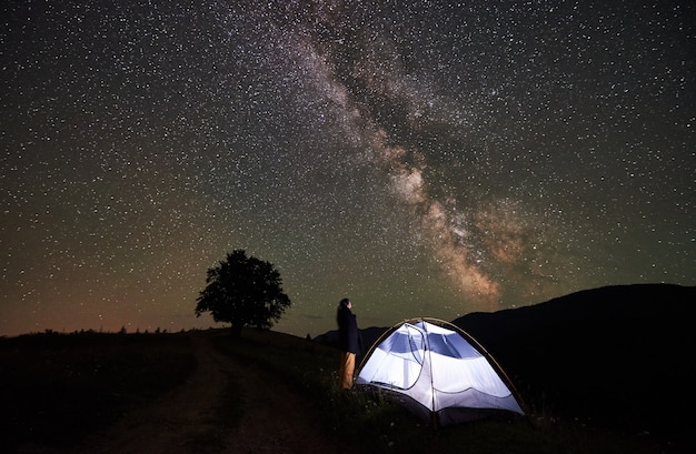 Touristique de femme se reposant la nuit en camping sous le ciel étoilé et la voie lactée