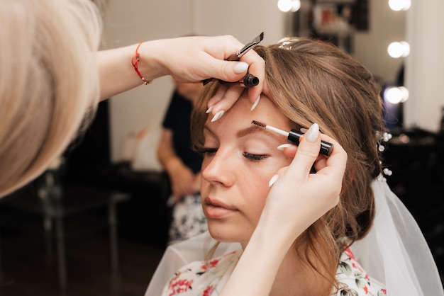 Tournage dans un salon de beauté. maquilleuse prépare la mariée avant le mariage le matin.