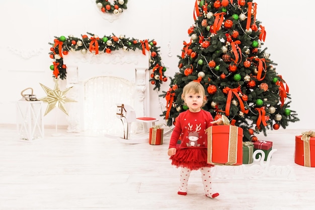 Le tournage du Nouvel An de la famille dans le studio Papa tient sa fille dans ses bras une fille accroche une boule de Noël sur un arbre de Noël