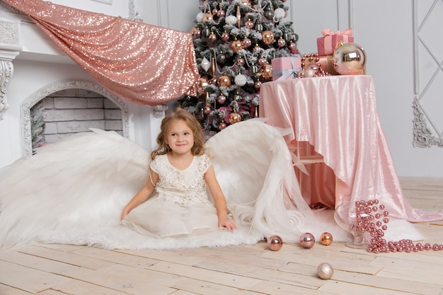 Tournage de Noël d'une jolie petite fille dans le studio avec des ailes