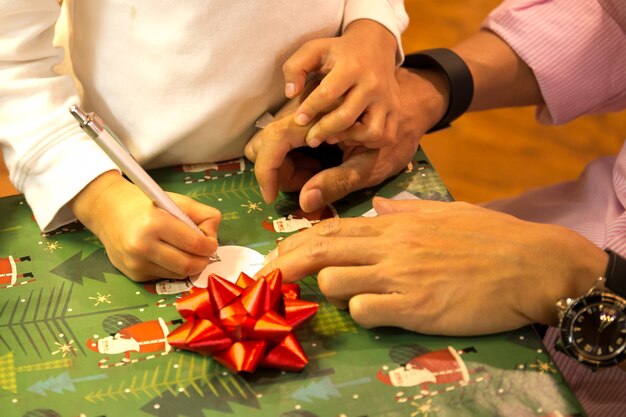 Tourné en basse lumière jeune garçon écrit une carte de Noël avec son père