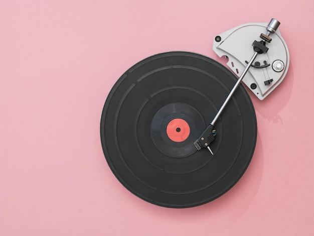 Tourne-disque vintage avec un disque vinyle rouge sur fond rose. Technique rétro pour jouer de la musique.