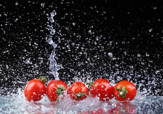 Tourné en studio avec gel de tomates cerises dans les éclaboussures d'eau sur fond noir