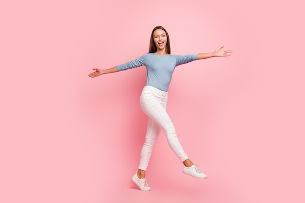 Tourné la taille du corps pleine longueur de joyeuse jolie jolie fille douce étendant ses bras sur les côtés pour vous inviter à être embrassé en marchant sur un fond de couleur pastel isolé en pull bleu