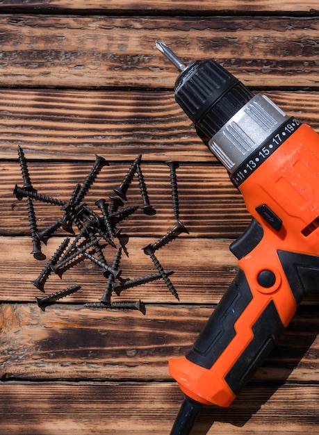 Tournevis orange et beaucoup de nouvelles vis sur une table en bois