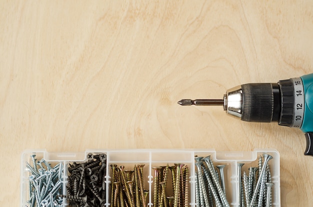 Tournevis et vis de différentes tailles dans une boîte sur une table en bois, vue de dessus, copiez l'espace. Outils de menuisier masculin pour le travail