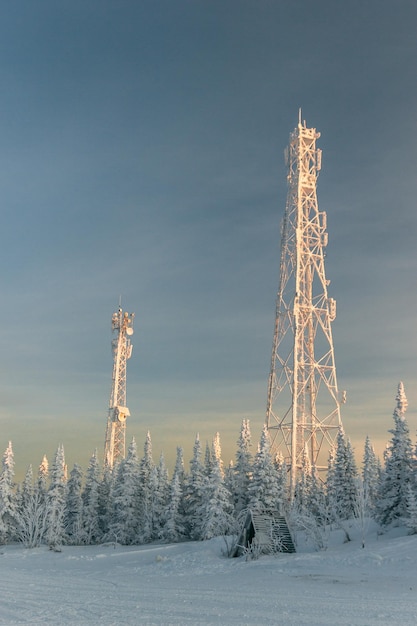 Tours de communication de neige au sommet de la montagne, entourées d'arbres de Noël enneigés