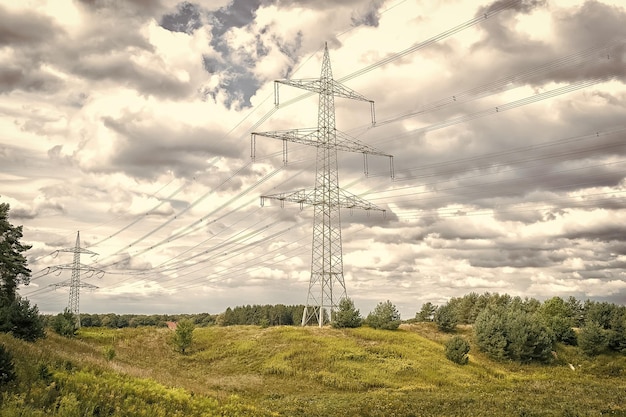 Tours électriques sur paysage naturel Tours de transmission sur ciel nuageux Structure de pylône électrique avec lignes électriques Poste haute tension extérieur Énergie et écologie