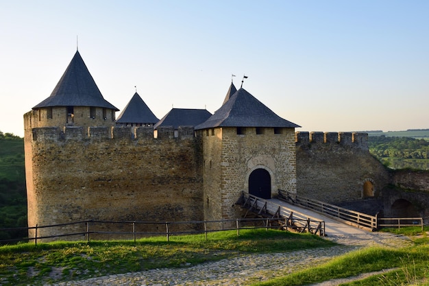 Tours d'une forteresse médiévale en pierre avec remparts, entrée voûtée et pont en bois