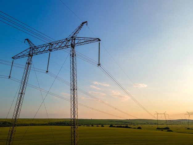 Tours haute tension avec lignes électriques au coucher du soleil.