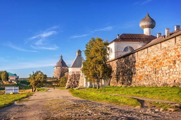 Tours de pierre du monastère Solovetsky et la route le long des rives de la baie de la prospérité sur les îles Solovetsky dans les rayons du soleil couchant