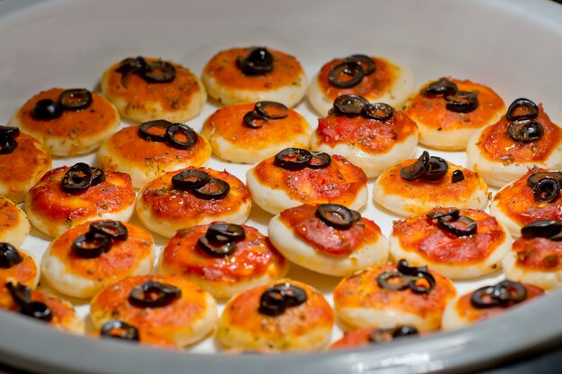 Tourtes à la viande rondes garnies d&#39;olives noires tranchées sur la ligne de buffet