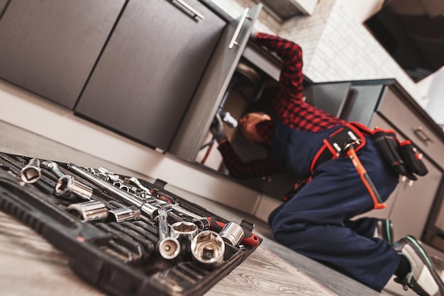 Tous les outils au cas où un bricoleur senior répare un lavabo dans la cuisine