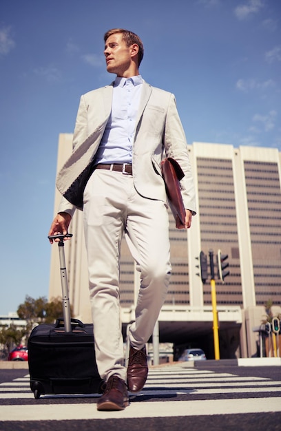 Tous travaillent sans jouer Photo d'un jeune homme d'affaires marchant avec une valise dans la ville