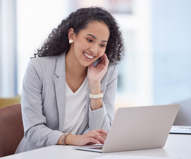 Tout a l'air bien d'où je suis. Photo d'une jolie jeune femme d'affaires assise seule dans son bureau et utilisant son ordinateur portable.