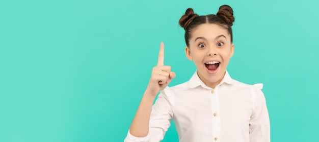 Tout commence par une idée Enfant heureux garder le doigt vers le haut fond bleu Retour à l'idée de l'école Visage d'enfant affiche horizontale adolescent fille portrait isolé bannière avec espace de copie