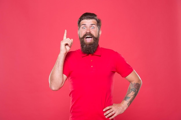 Tout commence par une idée Hipster inspiré pointant vers le haut sur fond rouge Un homme barbu a une idée Idée et concept Esprit créatif Grande idée pour la créativité et le résultat