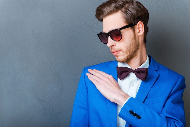 Tout doit être parfait. Jeune homme confiant dans les lunettes en train de brosser sa veste