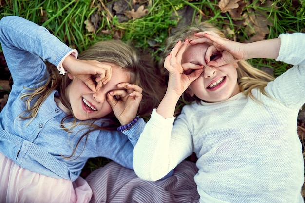 Tout est amusant quand on est jeune Portrait de deux petites sœurs allongées sur l'herbe à l'extérieur