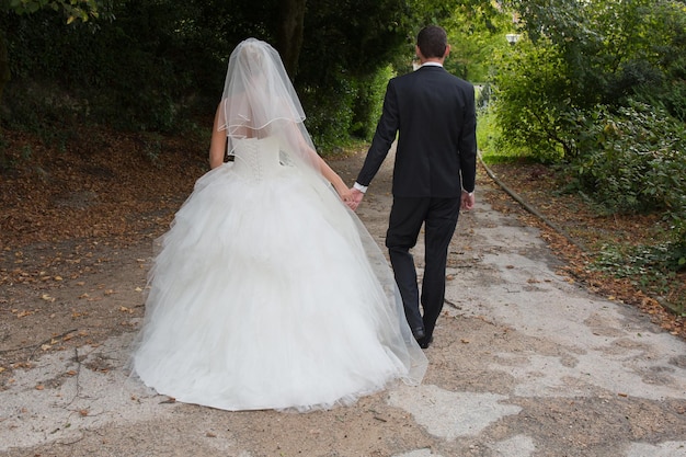 Tout juste marié. Une belle photo d'un couple juste marié marchant ensemble vers l'avenir. La femme a une belle robe de mariée et l'homme un costume noir.