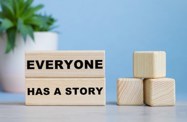 Photo tout le monde a une histoire mot sur des cubes en bois sur un bureau blanc.