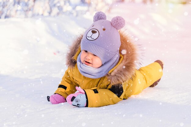 Tout-petit de 12 à 17 mois en vêtements d'hiver jaune a glissé et est tombé sur la glace en marchant dans un parc d'hiver