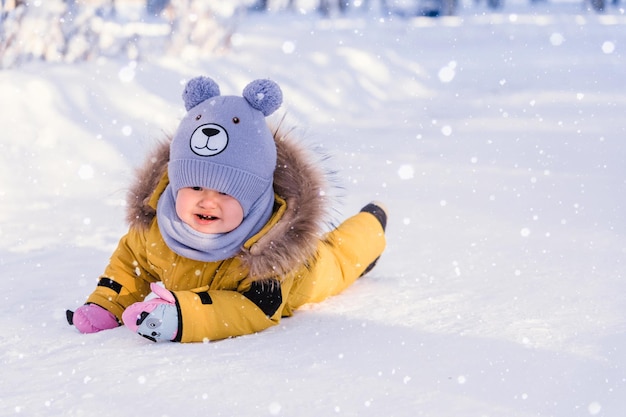 Tout-petit de 1217 mois en vêtements d'hiver jaunes a glissé et pleure en marchant dans un parc d'hiver