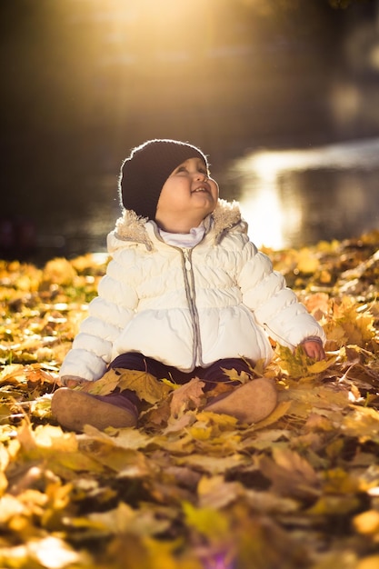 Un tout-petit assis sur des feuilles tombées