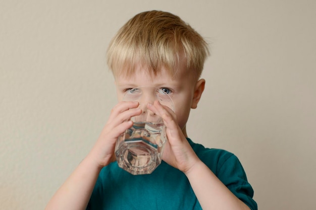 tout-petit garçon buvant un verre d'eau