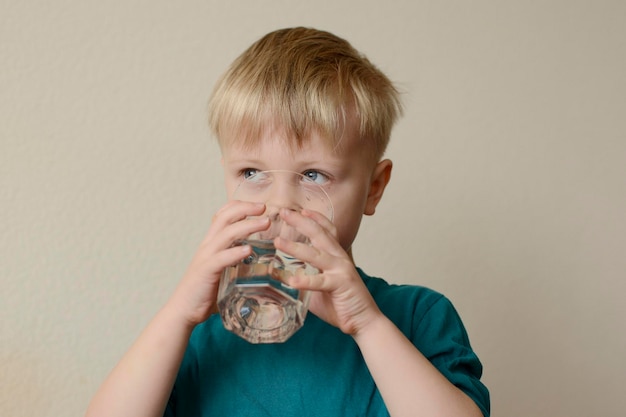 tout-petit garçon buvant un verre d'eau