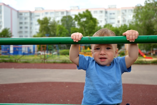 Un tout-petit grimpe l'échelle sportive sur l'aire de jeux. concept de mode de vie sportif. marcher au grand air. les enfants jouent sur l'aire de jeux en été.