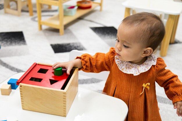 Tout-petit jouant avec la boîte de formes Montessori Imbucare