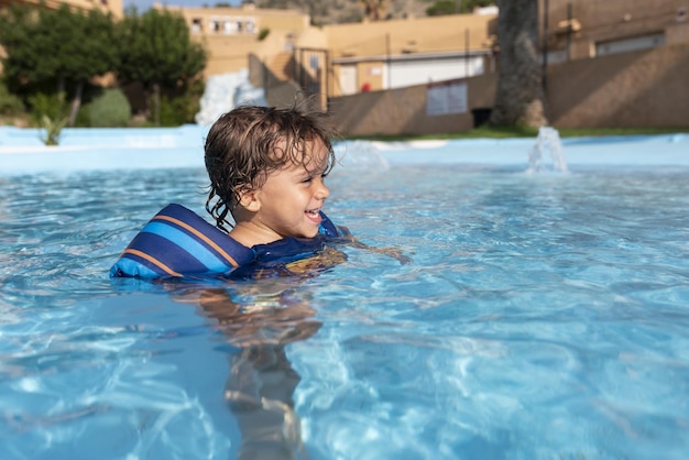 Tout-petit joue dans la piscine avec des flotteurs pour enfants L'été arrive dans l'hémisphère nord