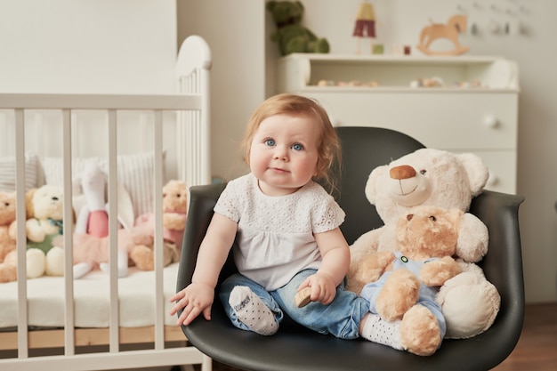 Tout-petit mignon assis sur une chaise près de jouets