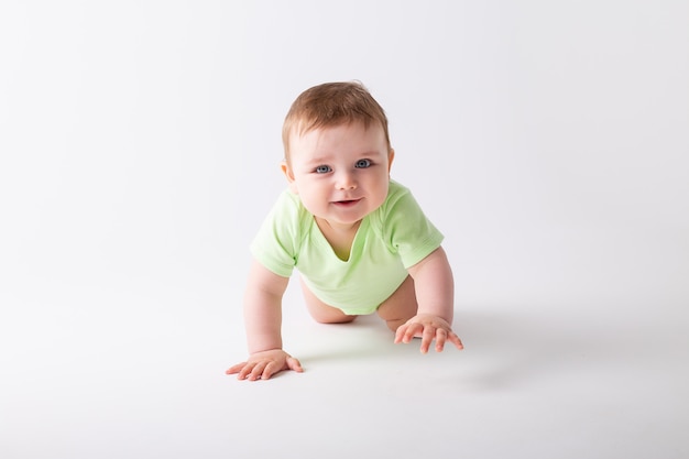 Tout-petit mignon en body vert est assis avec des pommes vertes