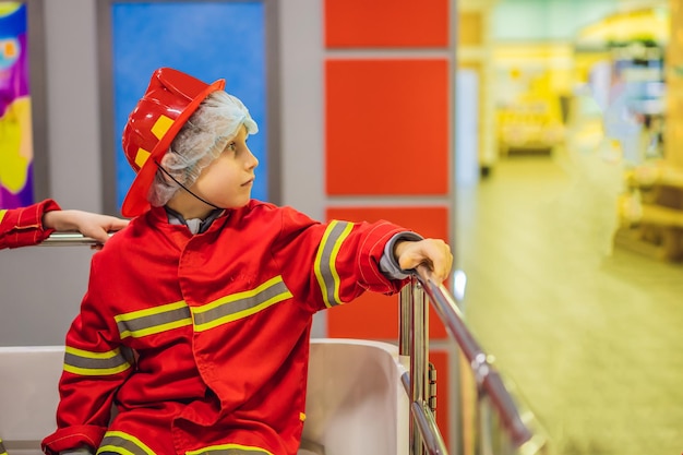 Photo tout-petit mignon expressif avec une tenue de pompier jouant au pompier