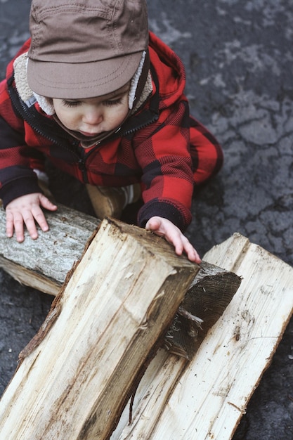 Photo un tout-petit mignon jouant avec du bois de chauffage à l'extérieur.