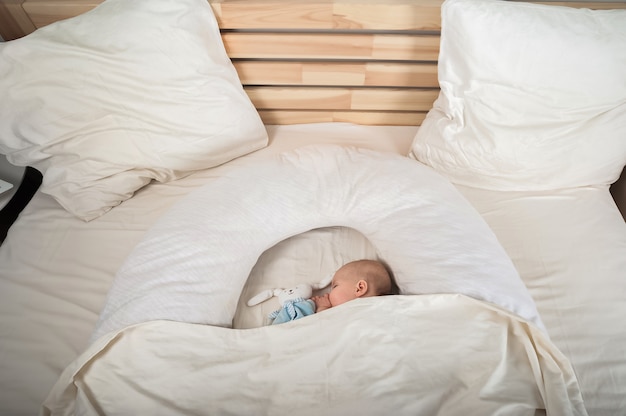 Tout-petit nouveau-né avec un jouet sur le gros plan de lit et copiez l'espace. L'enfant dort sur un grand lit