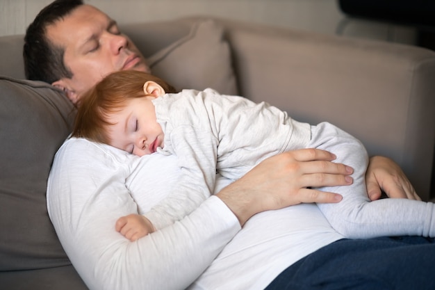 Tout-petit et papa dormant sur le canapé pendant la journée concept de jour pour enfants et soins parentaux se concentrent sur les mains