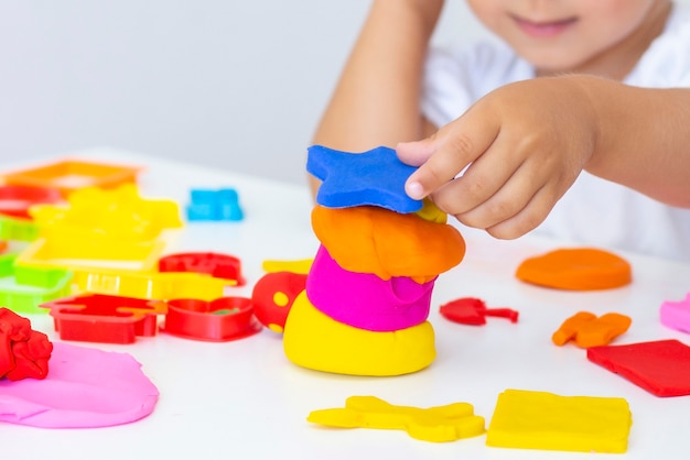 Tout-petit sculpte de pâte à modeler de couleur sur un tableau blanc