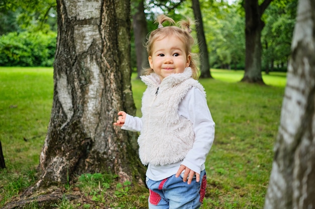 Le tout-petit se promène dans le parc d'été parmi les arbres
