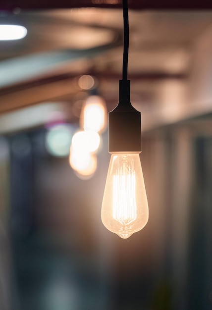 Tout ce qu'il faut, c'est une idée brillante Photo d'une ampoule suspendue au plafond dans un bureau vide le soir