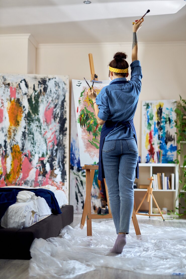 Photo toute la longueur de l'artiste féminine a levé la main avec un pinceau dedans en pensant à une nouvelle peinture