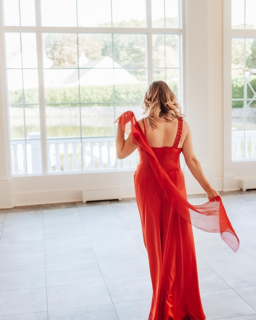 Photo toute la longueur d'une belle femme debout à la fenêtre à la maison